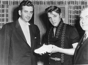 Elvis Presley and merchandiser Hank Saperstein show off an Elvis sneaker, one of many Elvis collectibles. See more Elvis pictures.