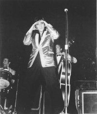 Person musician performing with musical instrument at black and white event.