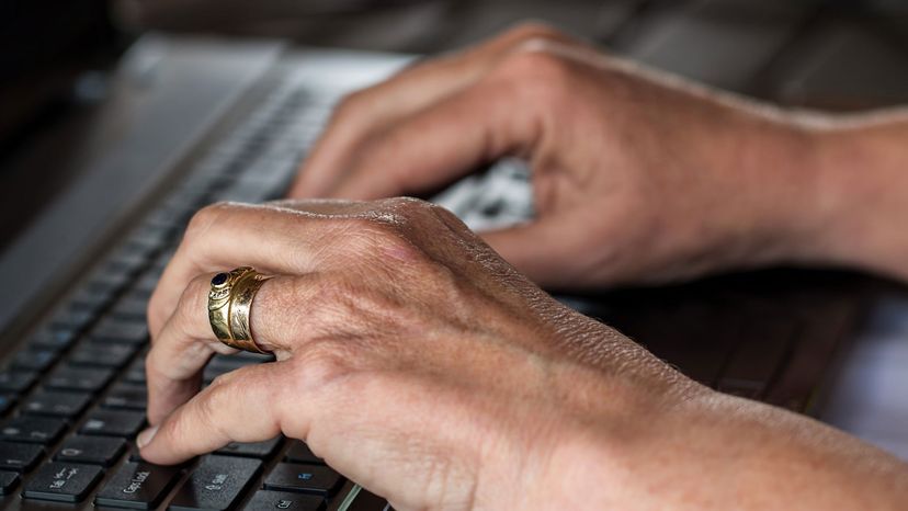 Person's hands typing on a computer keyboard.