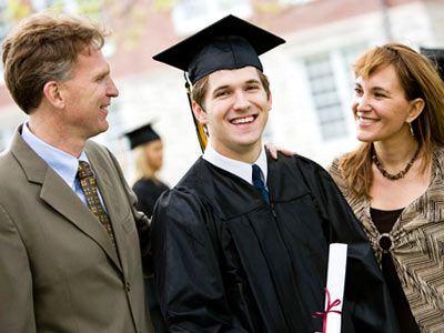 high school graduate stands with parents