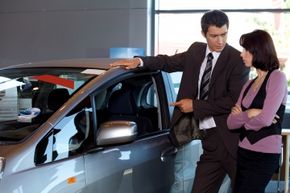 A car salesman shows a customer a car.