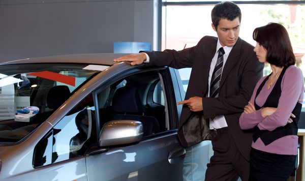 A car salesman shows a customer a car.