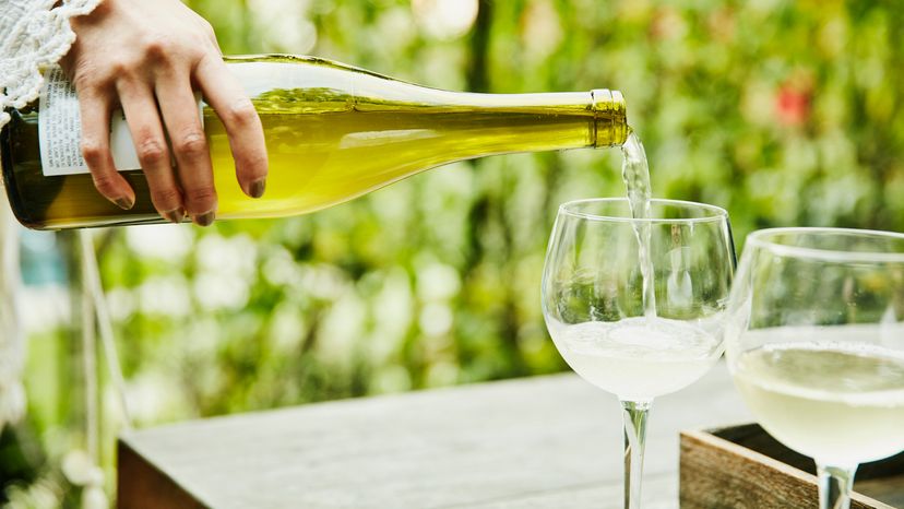 Woman pouring a white full bodied wine into wine goblets