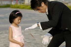 A young girl watches a magician perform.