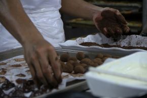 A worker makes chocolates in a kitchen.