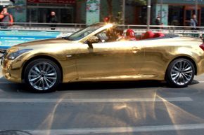 A driver takes a gold-plated Infiniti sports car on a test drive.