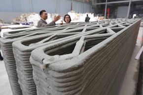 马一和(左)展示了他的公司在中国上海建造的3d打印房屋墙壁。他的公司计划在一天内制造10个这样的产品。”border=