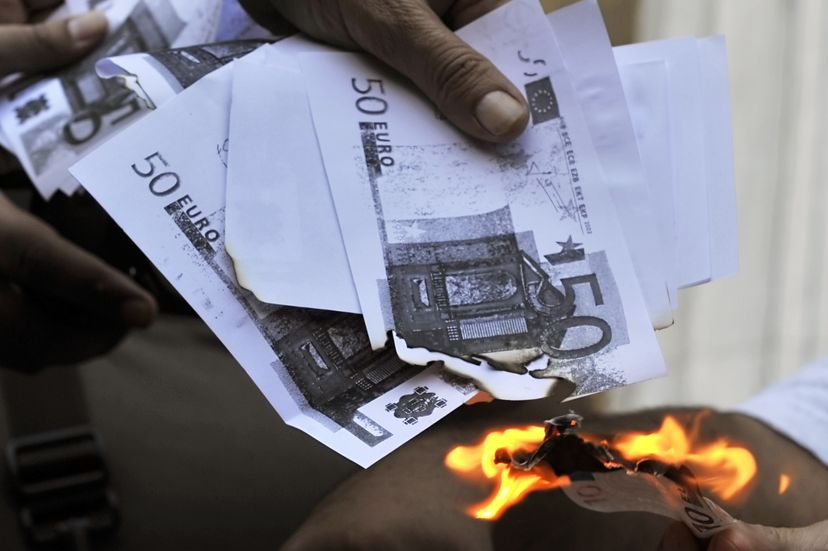 A protester sets fire to copies of euros in Greece in 2011. LOUISA GOULIAMAKI/AFP/Getty Images