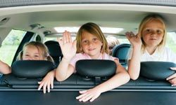 Girls waving in back seat of car