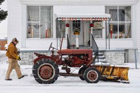 蒙蒂Bussard走回他的拖拉机1947 Farmall模型,后铲人行道后2014年Myersville暴风雪,Md,拖拉机是一台机器,革新了耕作。”width=