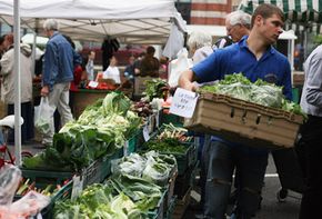 A man carries produce at a farmers' market.