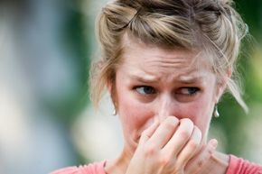 A woman holds her nose. 