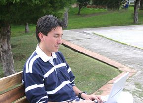 A young man using a laptop outdoors.&nbsp;