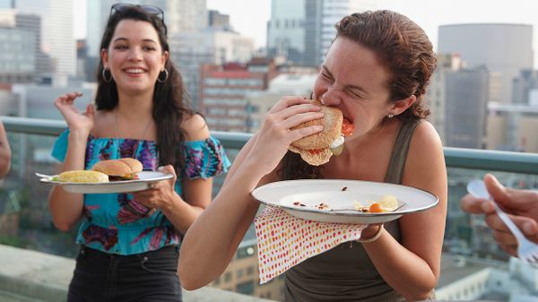 woman eating burger on city rooftop with friend