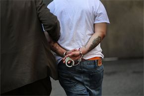 A man is brought to jail by a New York City police officer. If he's convicted of a felony, federal law would likely ban him from carrying a gun under most scenarios. Federally speaking, a felony refers to a crime that's punishable by more than a year of prison time. See more gun pictures.