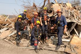 FEMA Urban Search and Rescue Task Force members pose with their rescue dogs in a neighborhood impacted by Hurricane Katrina.