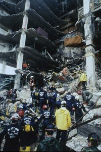 搜索和Rescue workers gather at the scene of the Oklahoma City bombing.“border=