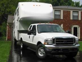 Pickup truck with fifth wheel hitch and trailer parked in a residential driveway.