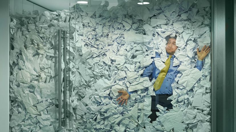 A man stuck in a conference room filled with paper