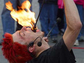 A fire eater extinguishes a burning prop in his mouth.