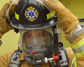 An Army National Guard firefighter puts on his SCBA (self-contained breathing apparatus) and helmet.