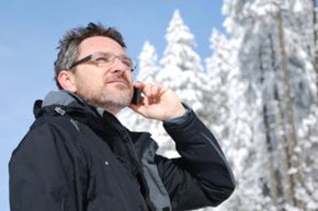 man on snow covered mountain talking on cell phone