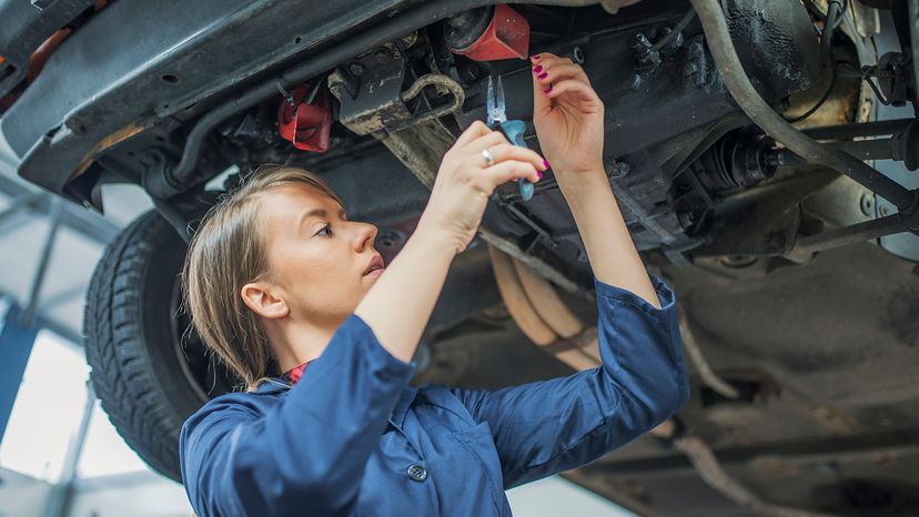 Mechanic inspecting a CV join on a car in auto repair shop