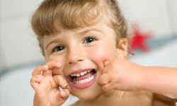 A young girl flosses her teeth.