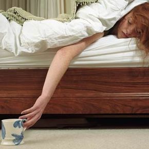 woman sick in bed reaches for her mug