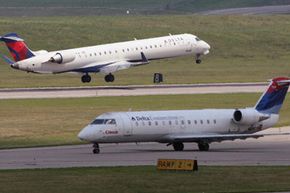 A Delta jet lands as another prepares for takeoff at the Cincinnati/Northern Kentucky International Airport near Covington, Ky.