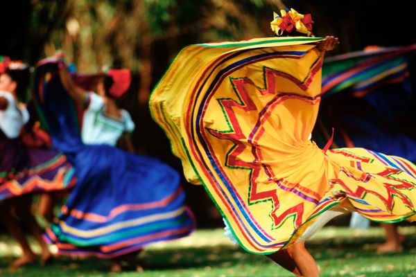 Women and men of diverse cultures dancing outdoors.
