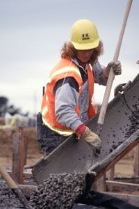 A worker pours concrete into formwork using a hose.