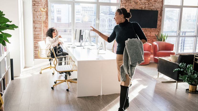 woman waving goodbye to another at office