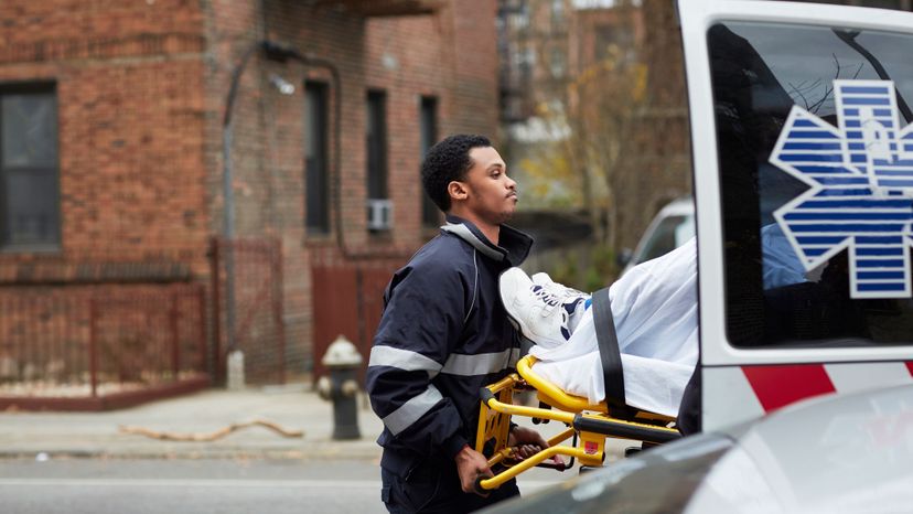 An EMT helps a patient into an ambulance