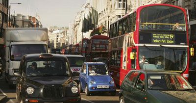 The G-Wiz huddles among taxi cabs, delivery trucks and hulking double-decker buses in London, England.