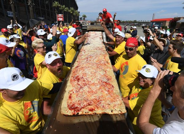 Men speed-eating pizza outdoors.