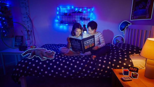 Child reading in bed at night in bedroom.