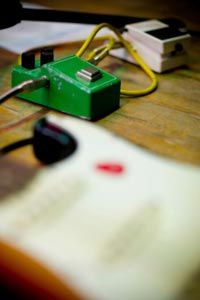 Guitar pedal and guitar in foreground