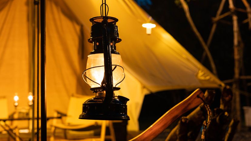 A vintage lantern near a tent in the forest