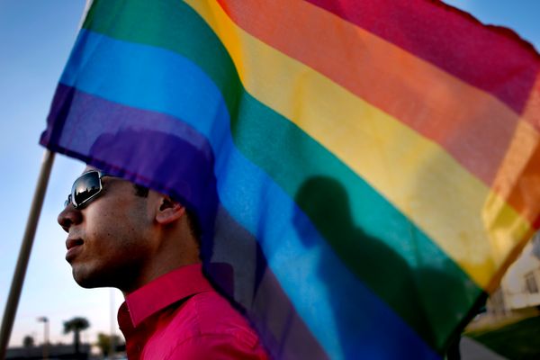 person holds lgbt flag that silhouettes someone