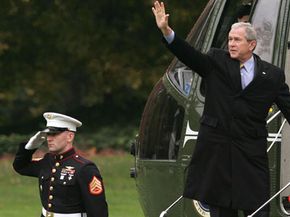 Former U.S. President George W. Bush (right) waves on the steps of the Marine One before his departure from the White House Nov. 19, 2007, in Washington, D.C. Watch Stuff You Should Know on presidential perks.