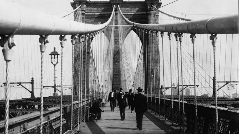 People walk the pedestrian pathway of the brooklyn bridge