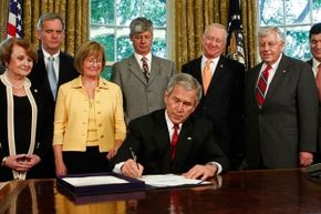 Surrounded by members of Congress, U.S. President George W. Bush signs the Genetic Information Nondiscrimination Act of 2008 during a ceremony in the Oval Office at the White House.