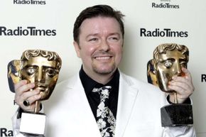 Actor and writer Ricky Gervais poses holding two awards for "The Office" at the British Academy Television Awards in 2003.”border=