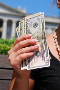 A young woman holds several bills on a bench outside the Treasury Department (background) in Washington DC