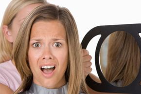 Hairdresser holding mirror for woman