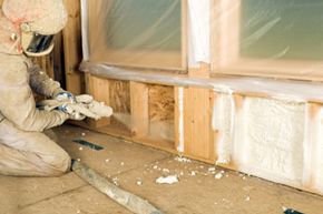 建筑工人喷涂发泡绝缘泡沫”width=