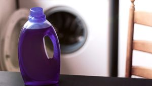 Purple detergent bottle on a table in front of a frontload washer