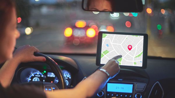 Rear view of woman driving car and touching screen of navigation system