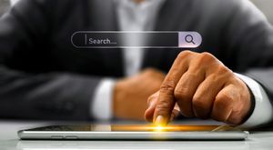 A search bar appears over a hand that's touching a tablet
